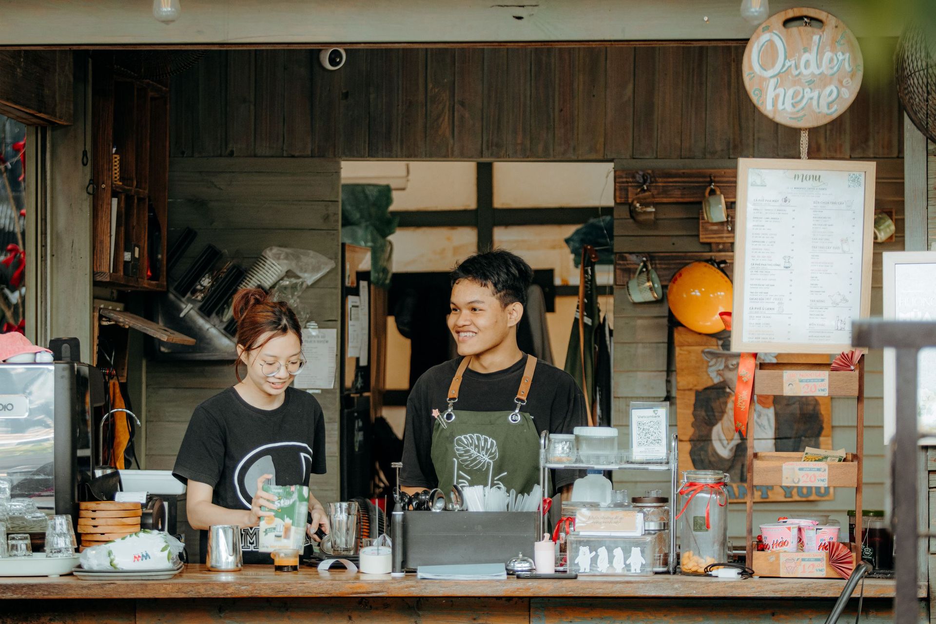 Two baristas at the counter of a small café in Vietnam, looking up to take an order